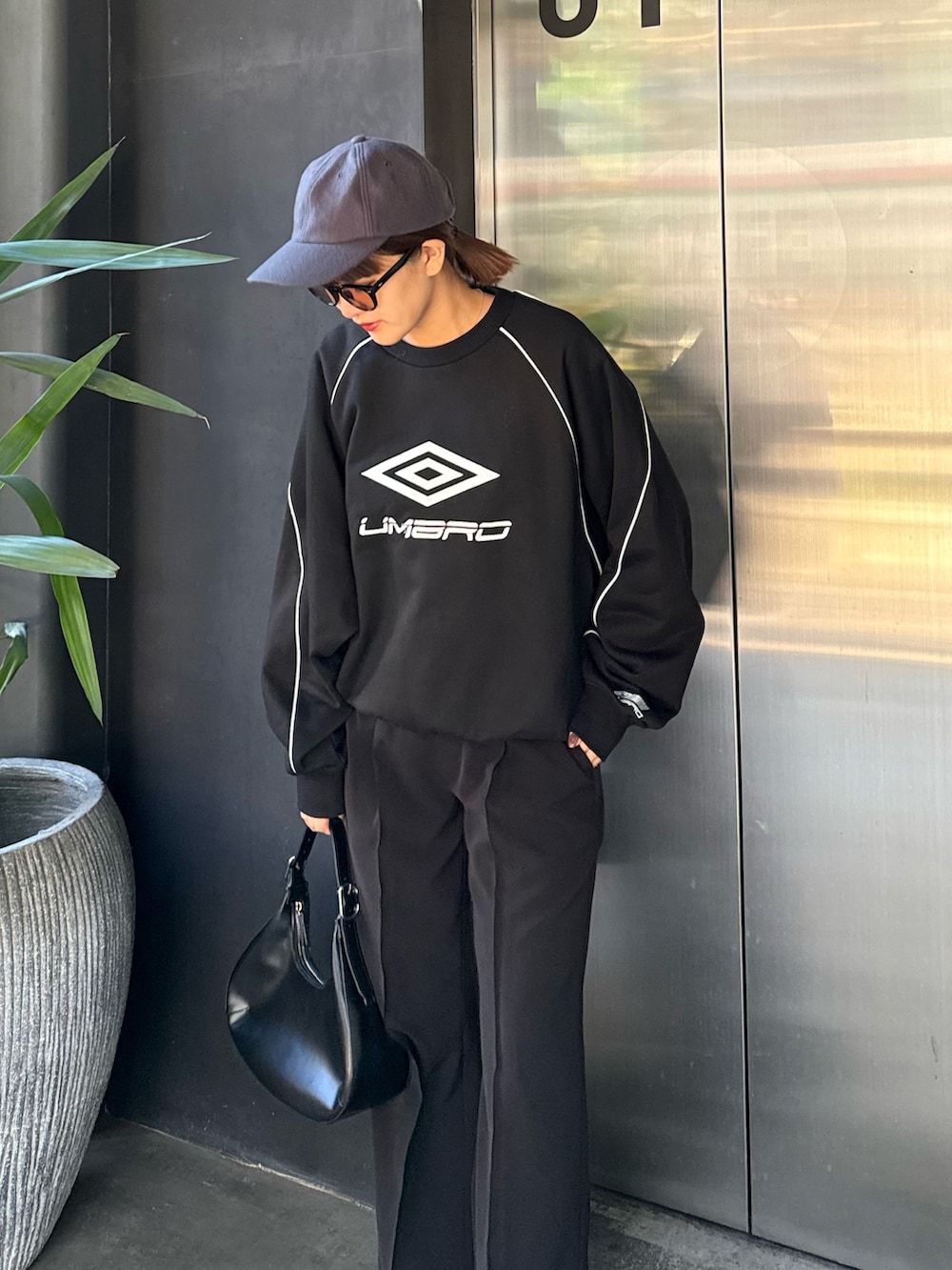 ブルー系のスウェット、ブラック系のハンドバッグ、ブラック系のサングラスを着用したレディースの冬コーディネートの2枚目の写真