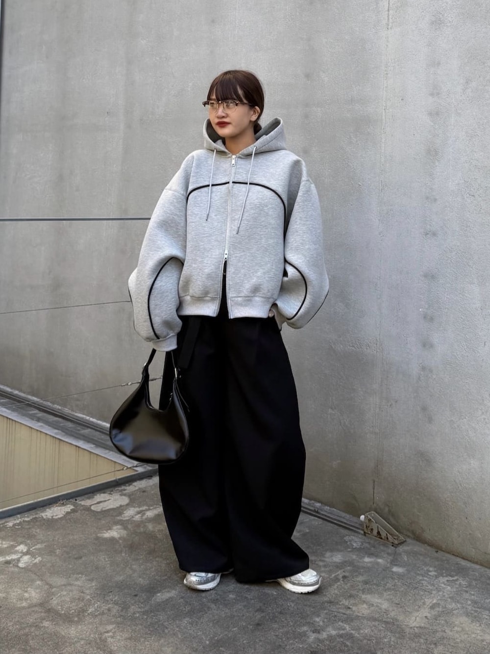 グレー系のパーカー、ブラック系のスラックス、ブラック系のハンドバッグを着用したレディースの冬コーディネートの3枚目の写真