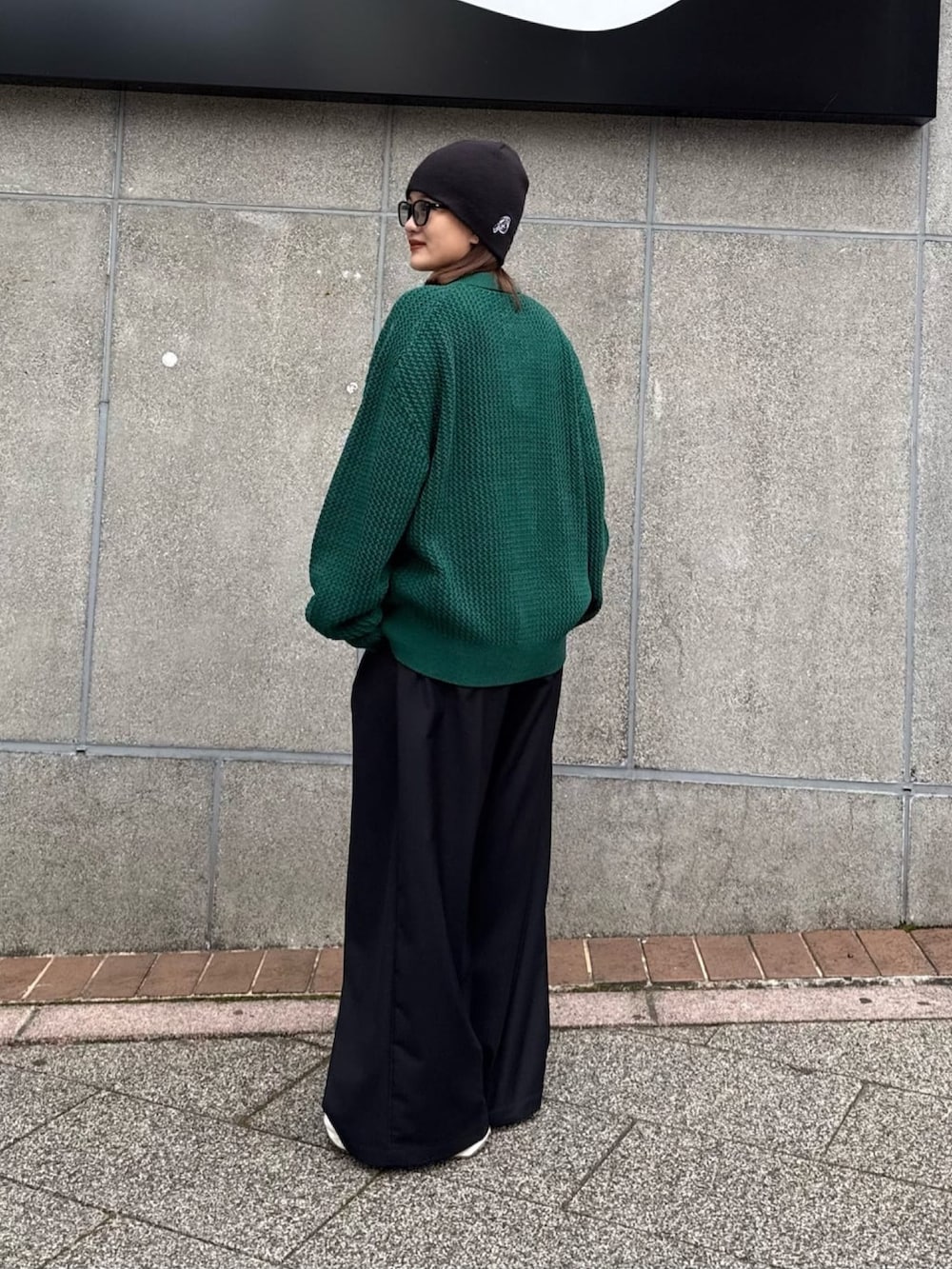 グリーン系のニット/セーター、グレー系のスラックスを着用したレディースの冬コーディネートの2枚目の写真