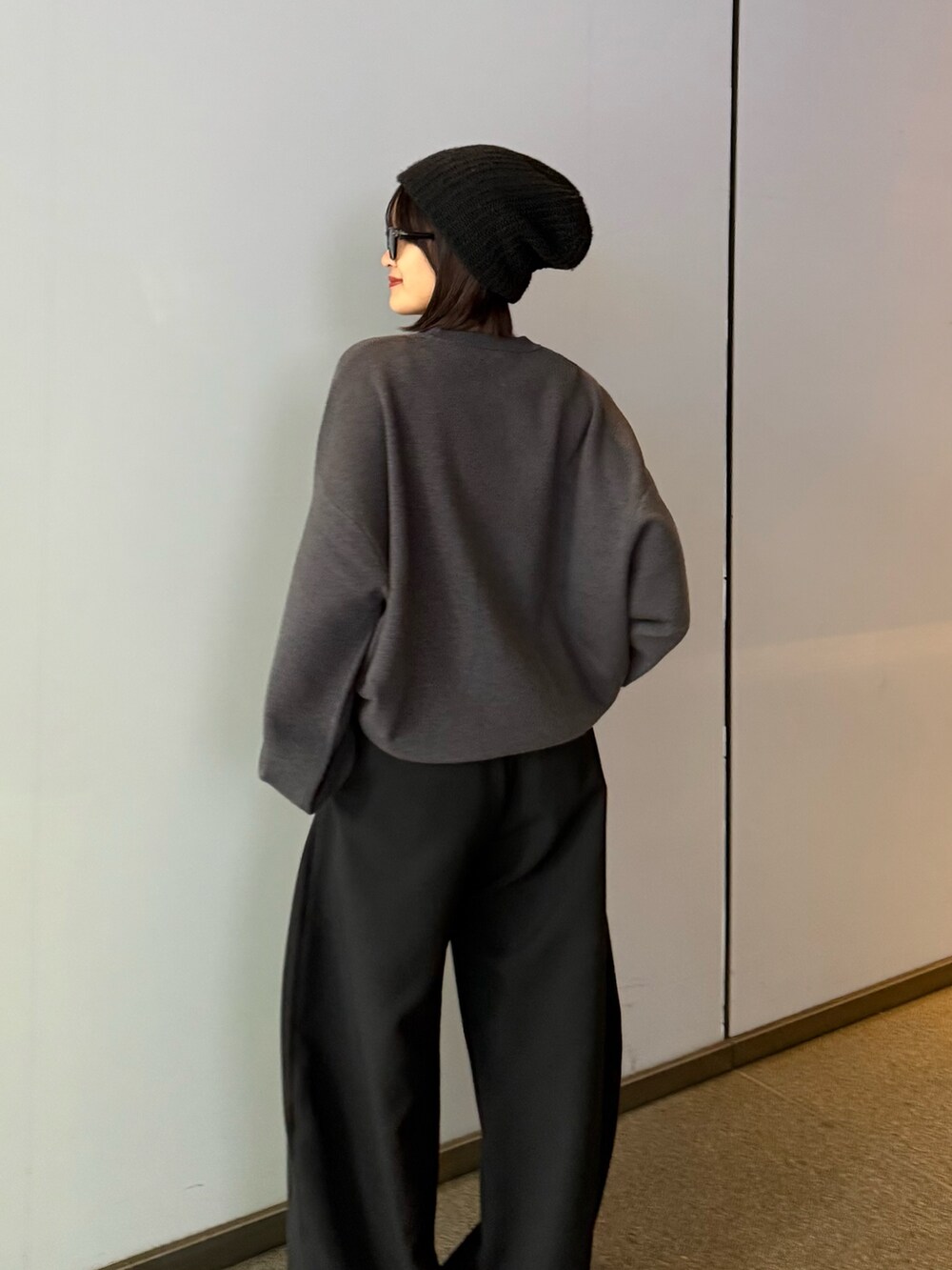 グレー系のニット/セーター、ブラック系のスラックス、ブラック系のサングラスを着用したレディースの秋コーディネートの3枚目の写真