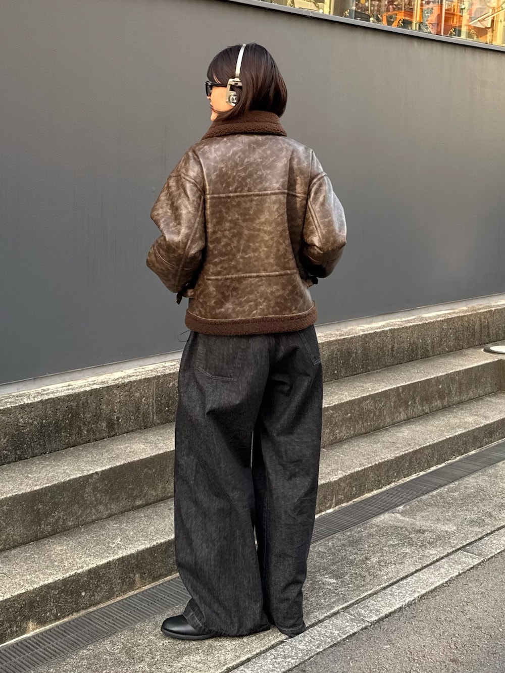 ブラウン系のブルゾン、ブラック系のデニムパンツを着用したレディースの秋コーディネートの4枚目の写真