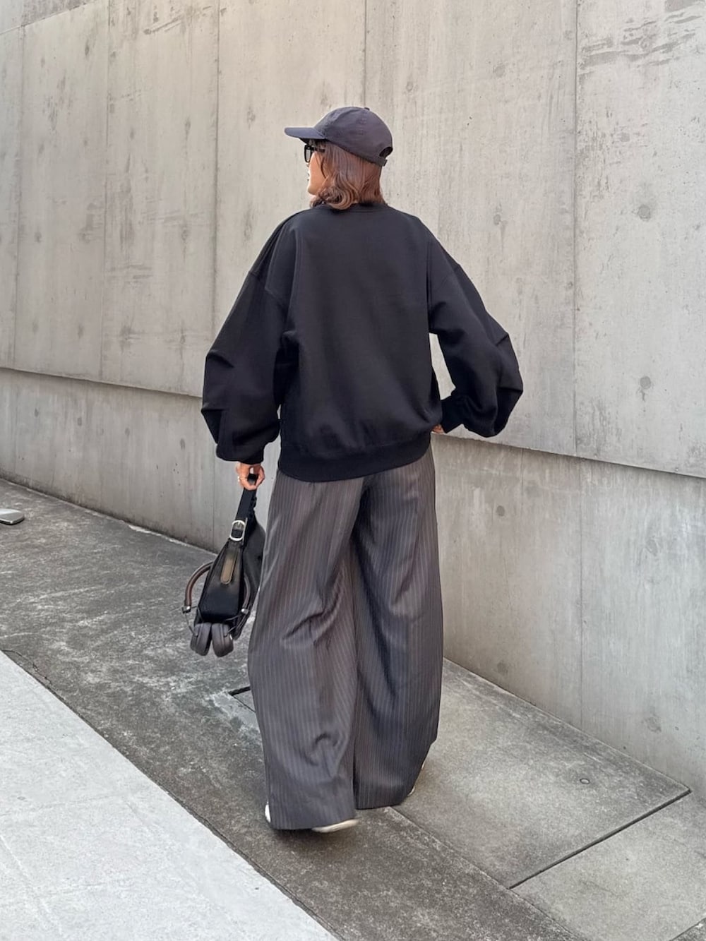 ホワイト系のスウェット、グレー系のスラックス、ブラック系のハンドバッグを着用したレディースの冬コーディネートの3枚目の写真