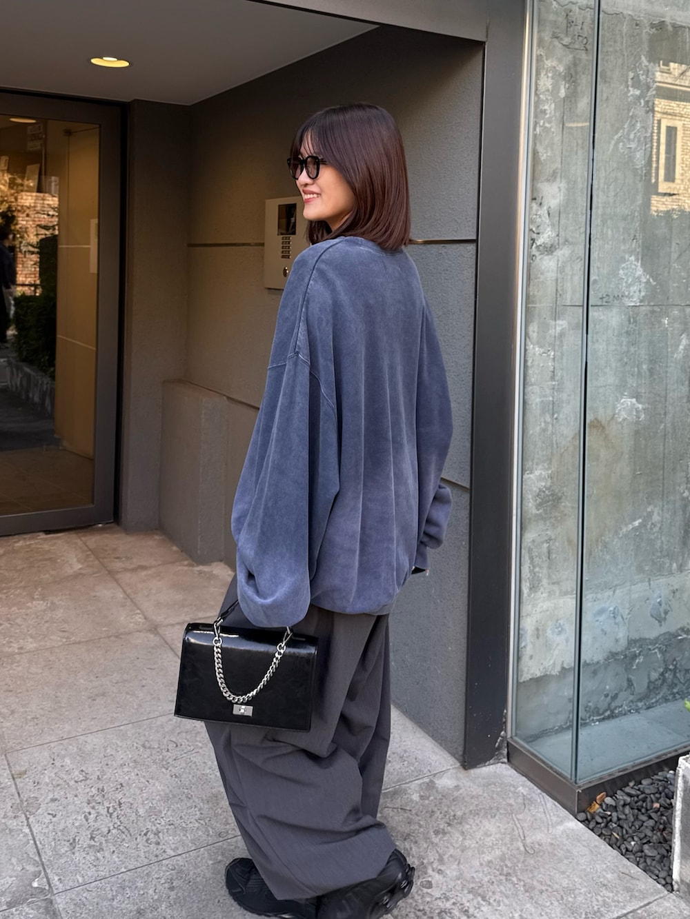 ブルー系のスウェット、ブラック系のショルダーバッグ、グレー系のスラックスを着用したレディースの冬コーディネートの4枚目の写真