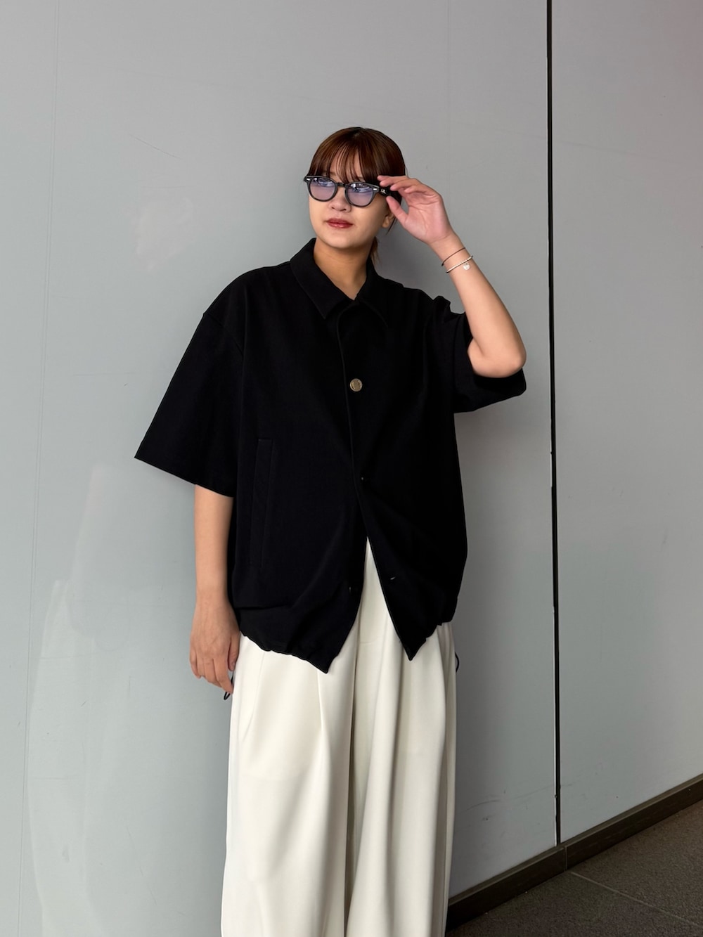 ブラック系のシャツ/ブラウス、グレー系のスラックスを着用したレディースの春コーディネートの2枚目の写真