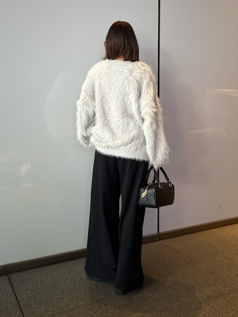 ブラック系のスラックス、ブラック系のトートバッグ、グレー系のニット/セーターを着用したレディースの冬コーディネートの3枚目の写真