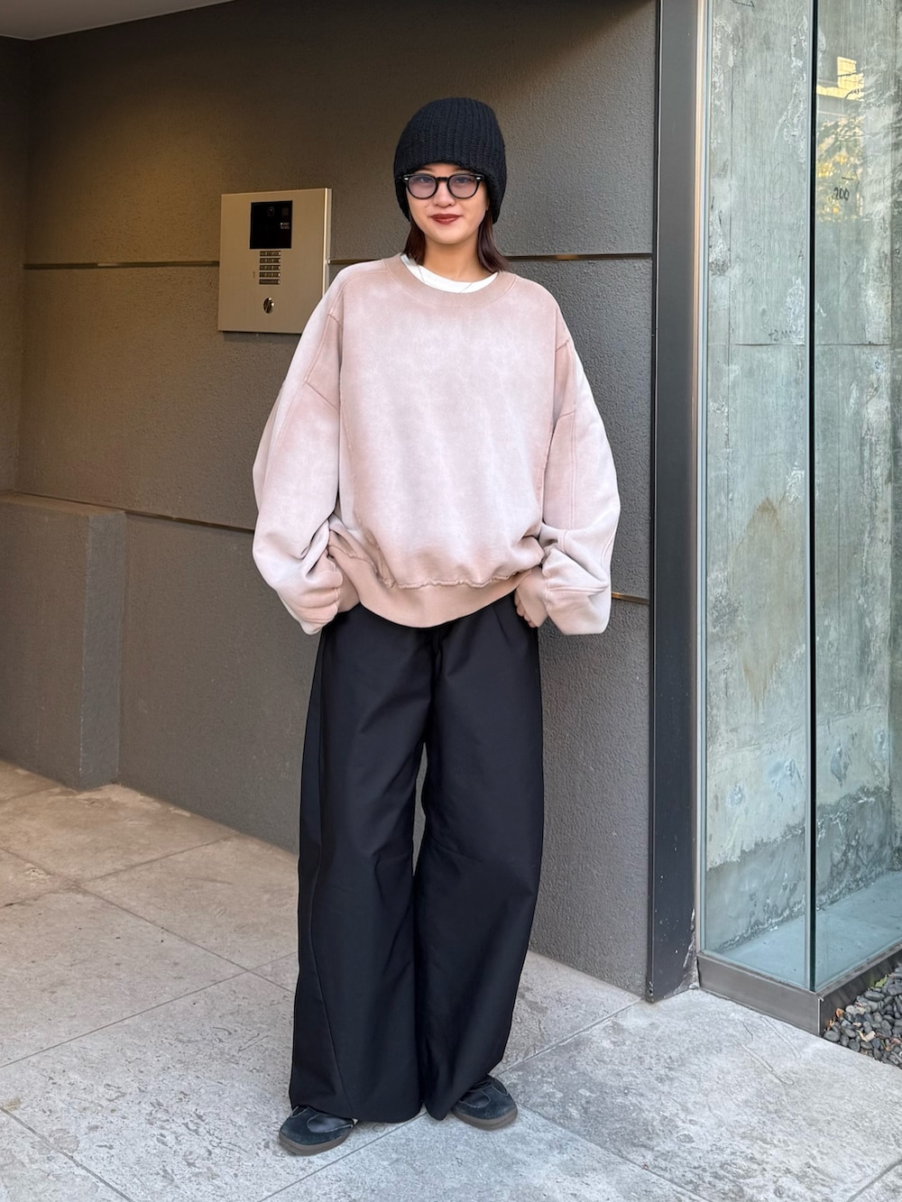 ベージュ系のスウェット、ブラック系のスラックス、ブラック系のサングラスを着用したレディースの冬コーディネートの2枚目の写真