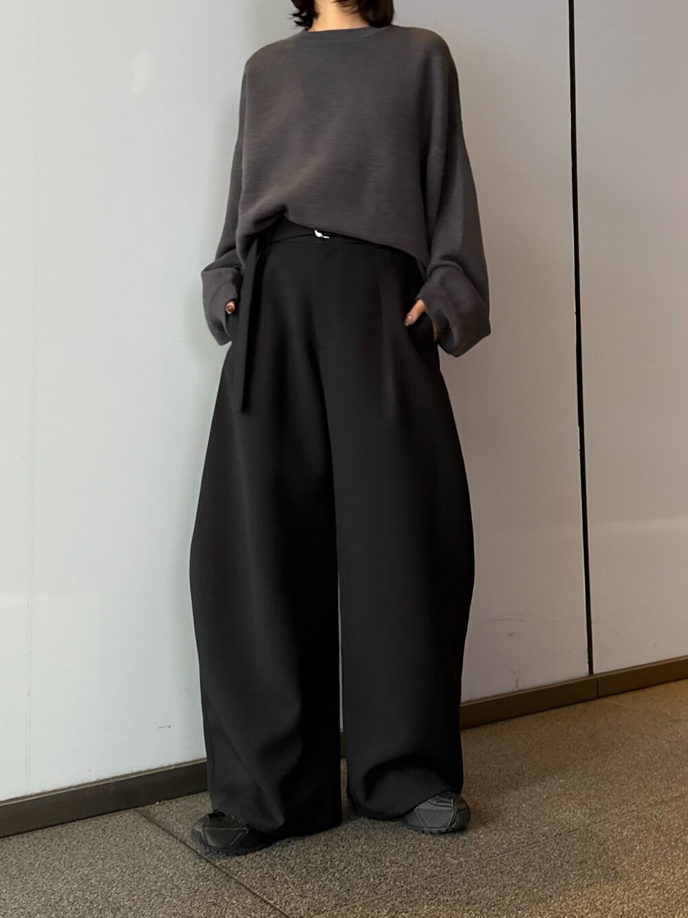 グレー系のニット/セーター、ブラック系のスラックス、ブラック系のサングラスを着用したレディースの秋コーディネートの2枚目の写真