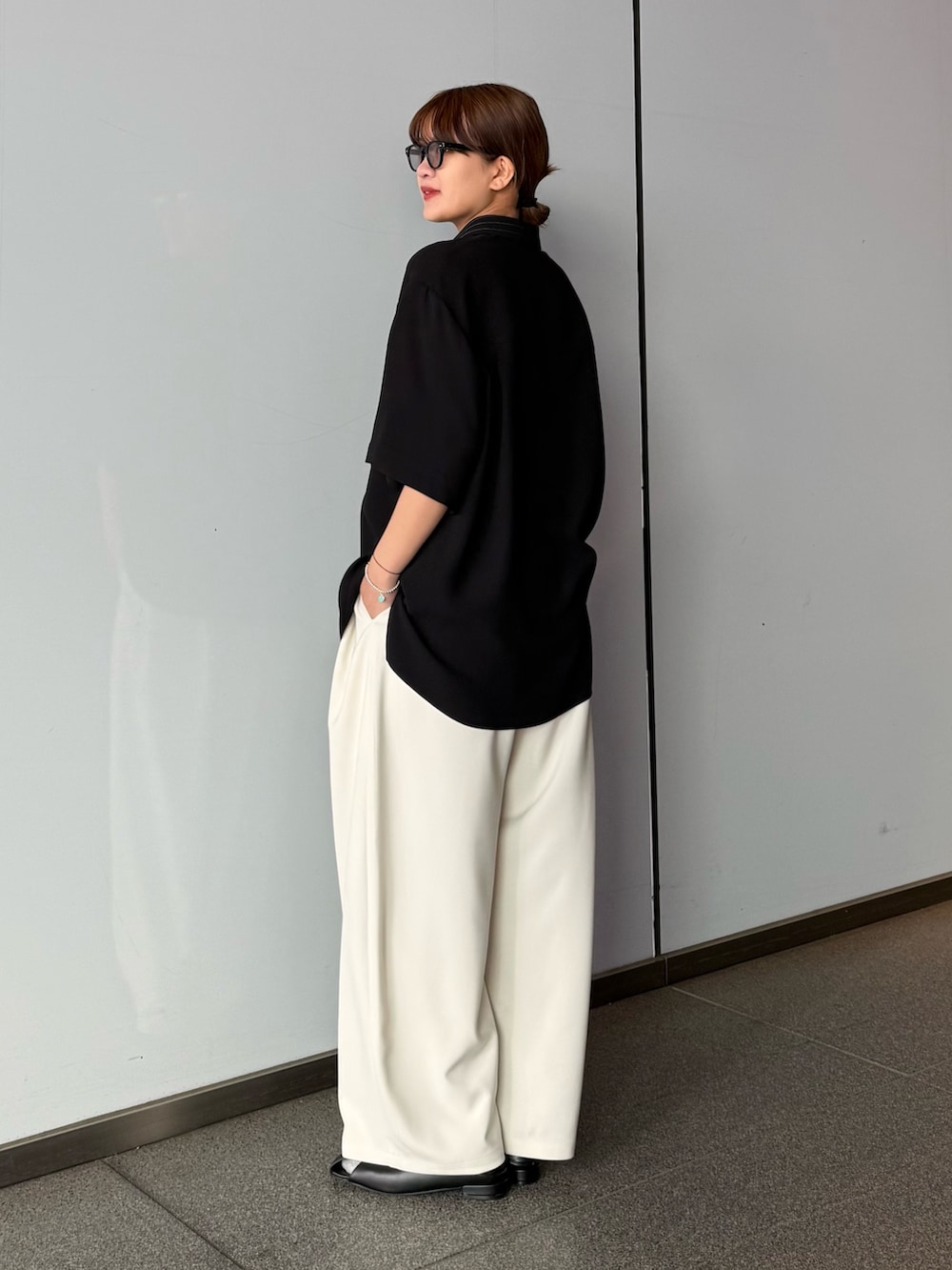 ブラック系のシャツ/ブラウス、グレー系のスラックスを着用したレディースの春コーディネートの3枚目の写真