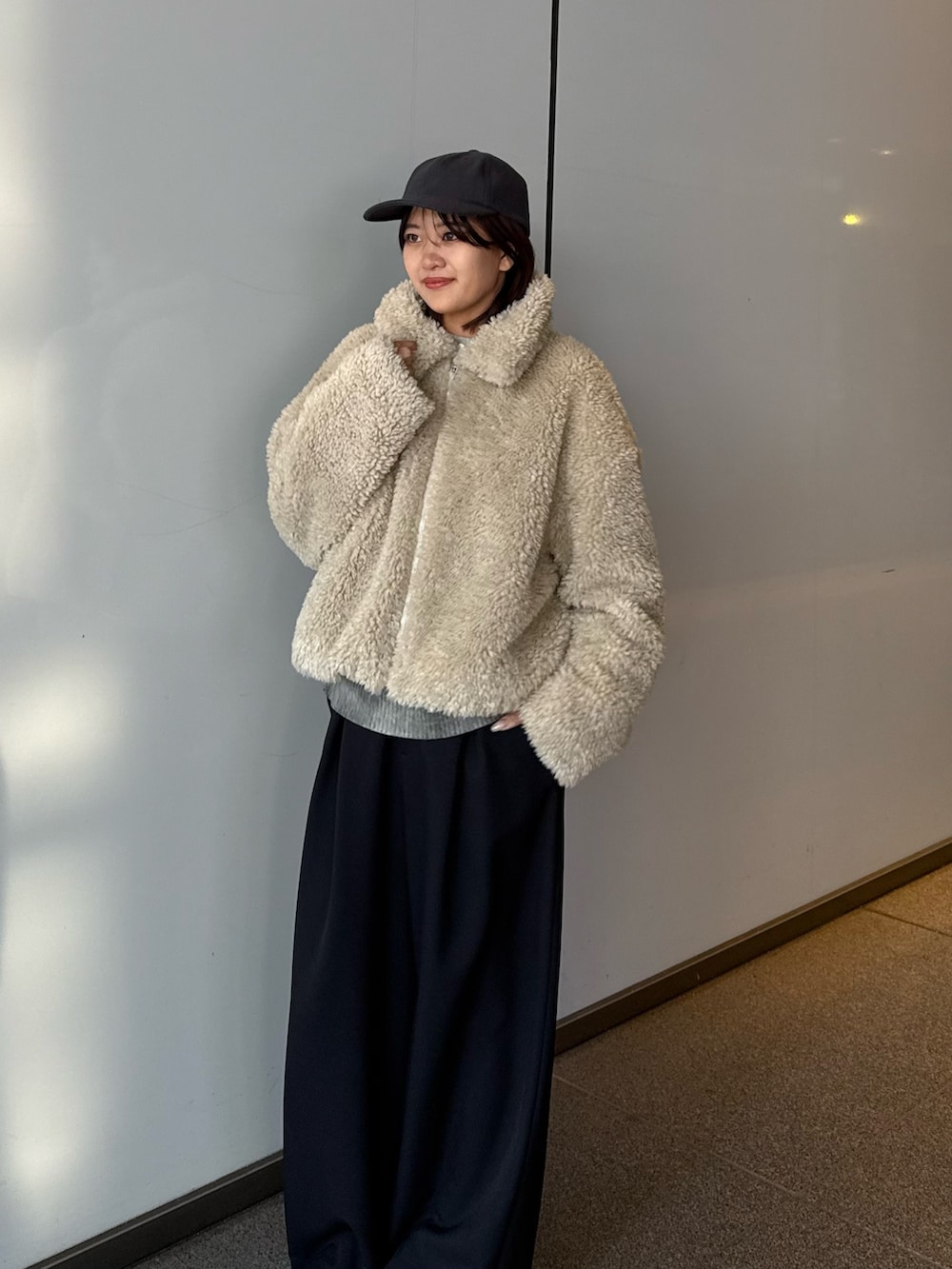 ベージュ系のブルゾン、ブラック系のスラックスを着用したレディースの冬コーディネートの4枚目の写真