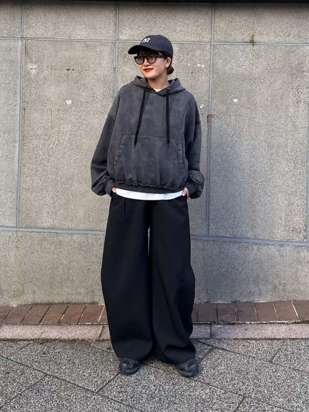 ブラック系のパーカー、ブラック系のスラックス、ブラック系のサングラスを着用したレディースの冬コーディネートの8枚目の写真