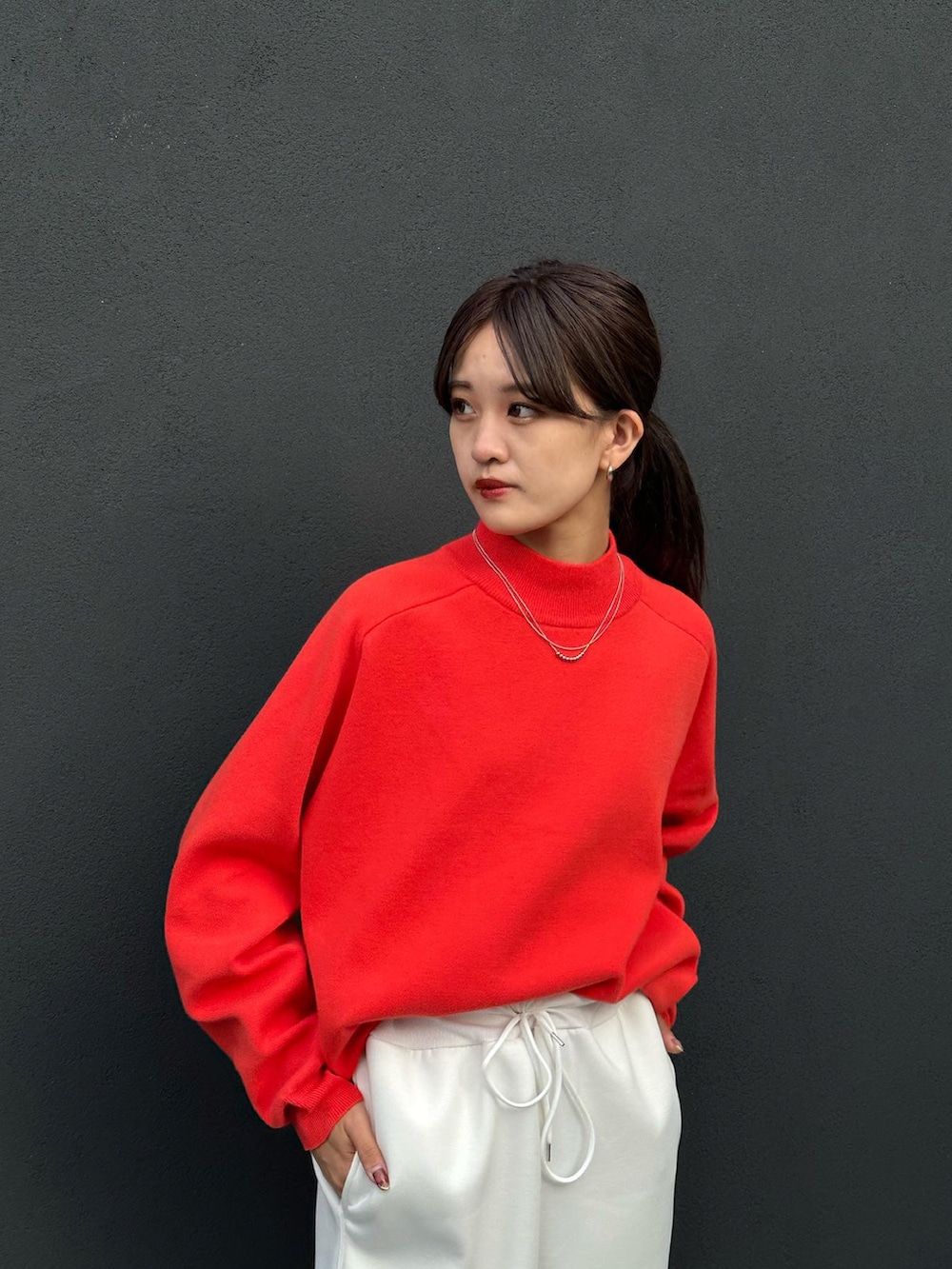 ホワイト系のスウェットパンツ、オレンジ系のニット/セーター、ホワイト系のスニーカーを着用したレディースの秋コーディネートの2枚目の写真