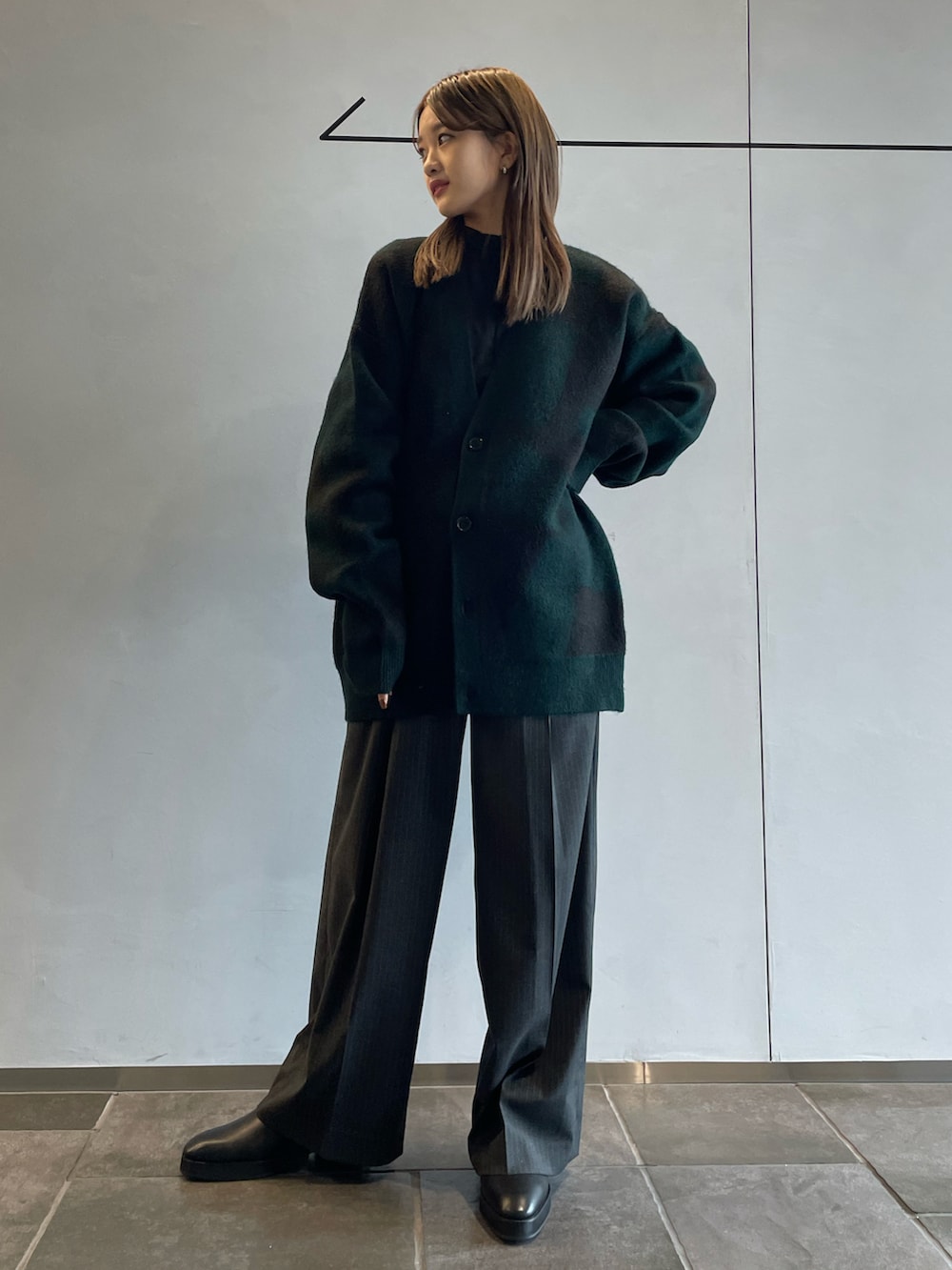 グリーン系のカーディガン/ボレロ、グレー系のスラックス、ブラック系のブーツを着用したレディースの秋コーディネートの3枚目の写真