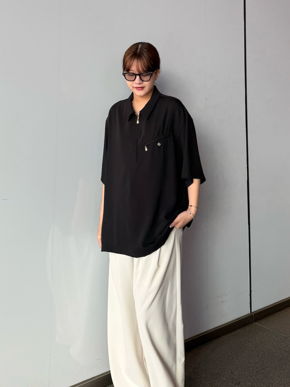 グレー系のスラックス、ブラック系のポロシャツを着用したレディースの春コーディネートの5枚目の写真