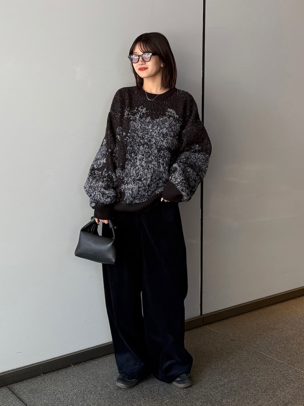 ブラック系のチェスターコート、ブラック系のニット/セーター、ブラック系のトートバッグを着用したレディースの秋コーディネートの2枚目の写真