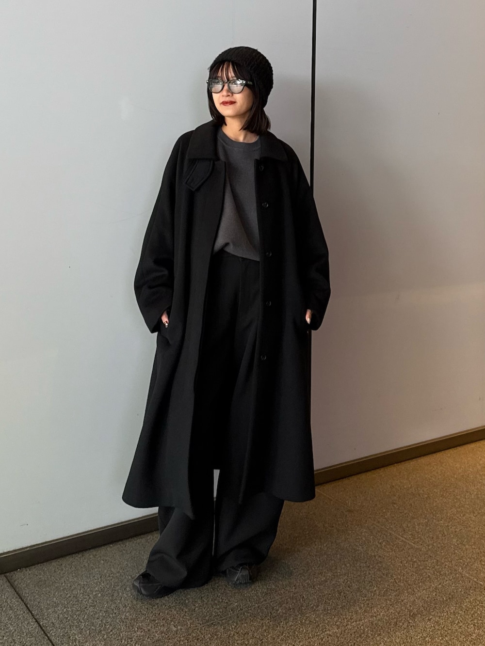 ブラック系のステンカラーコート、ブラック系のステンカラーコート、グレー系のニット/セーターを着用したレディースの秋コーディネートの4枚目の写真