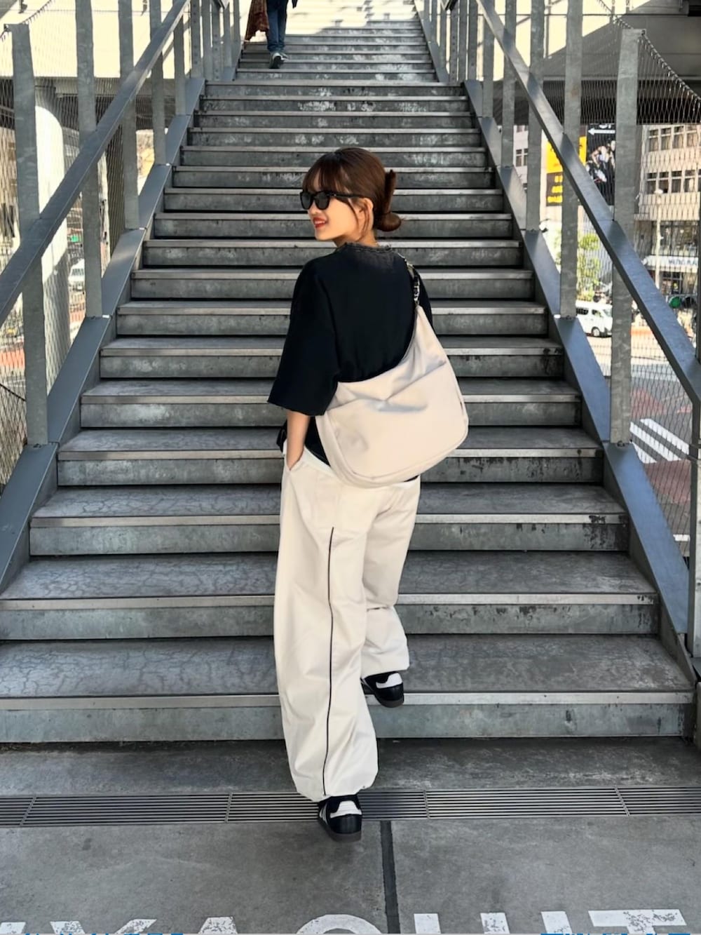 ブラック系のTシャツ/カットソー、グレー系のショルダーバッグ、ホワイト系のパンツを着用したレディースの春コーディネートの3枚目の写真