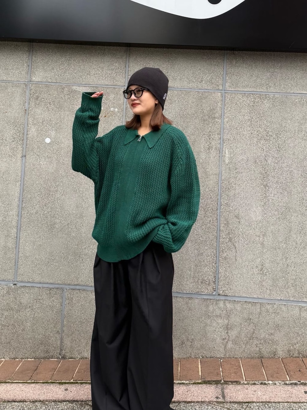 グリーン系のニット/セーター、グレー系のスラックスを着用したレディースの冬コーディネートの3枚目の写真