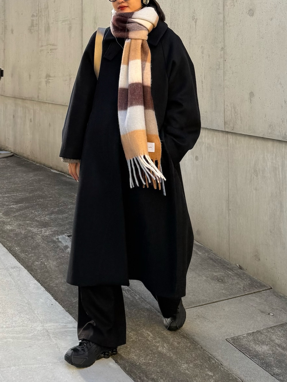 ブラック系のチェスターコート、ブラック系のその他アウター、ブラウン系のマフラーを着用したレディースの秋コーディネートの6枚目の写真