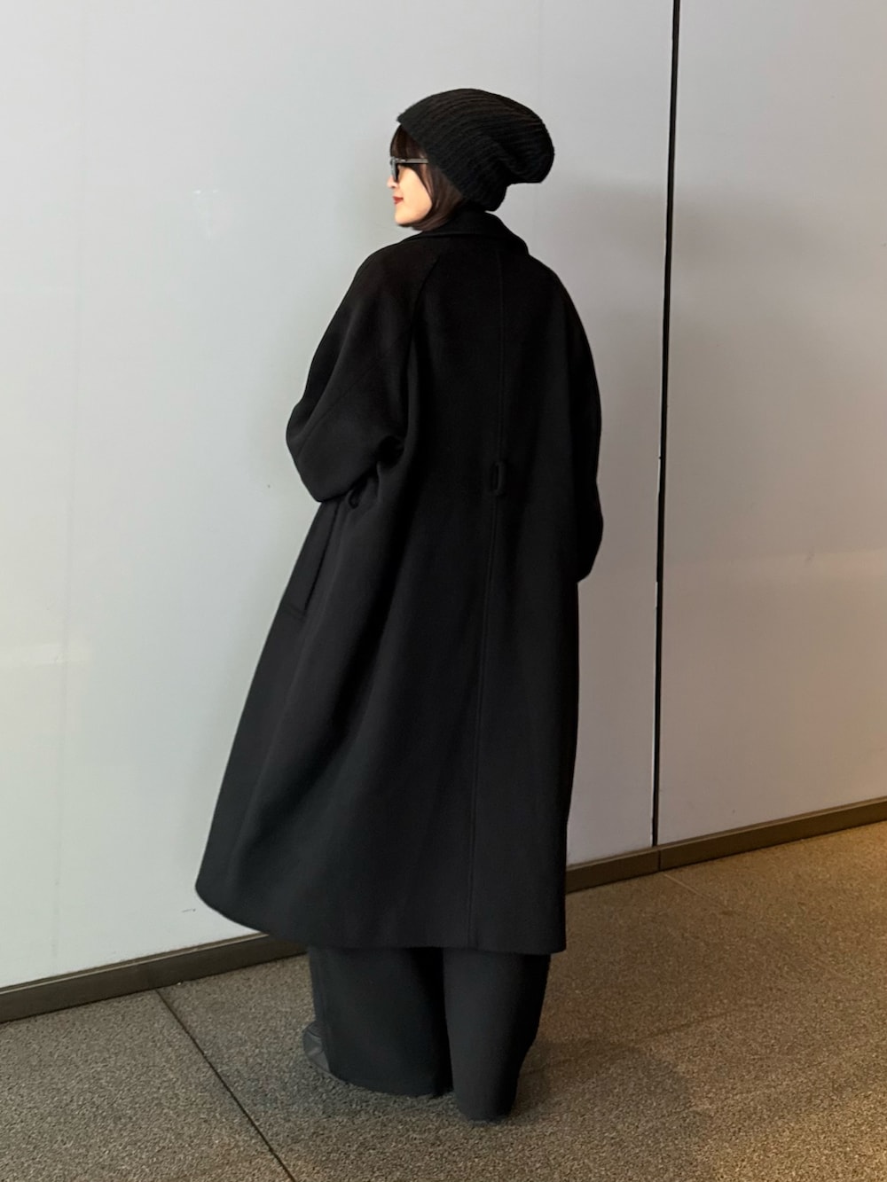 ブラック系のステンカラーコート、ブラック系のステンカラーコート、グレー系のニット/セーターを着用したレディースの秋コーディネートの2枚目の写真