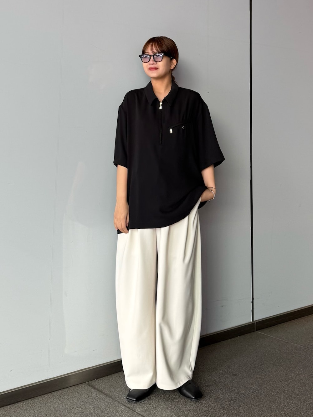 グレー系のスラックス、ブラック系のポロシャツを着用したレディースの春コーディネートの2枚目の写真