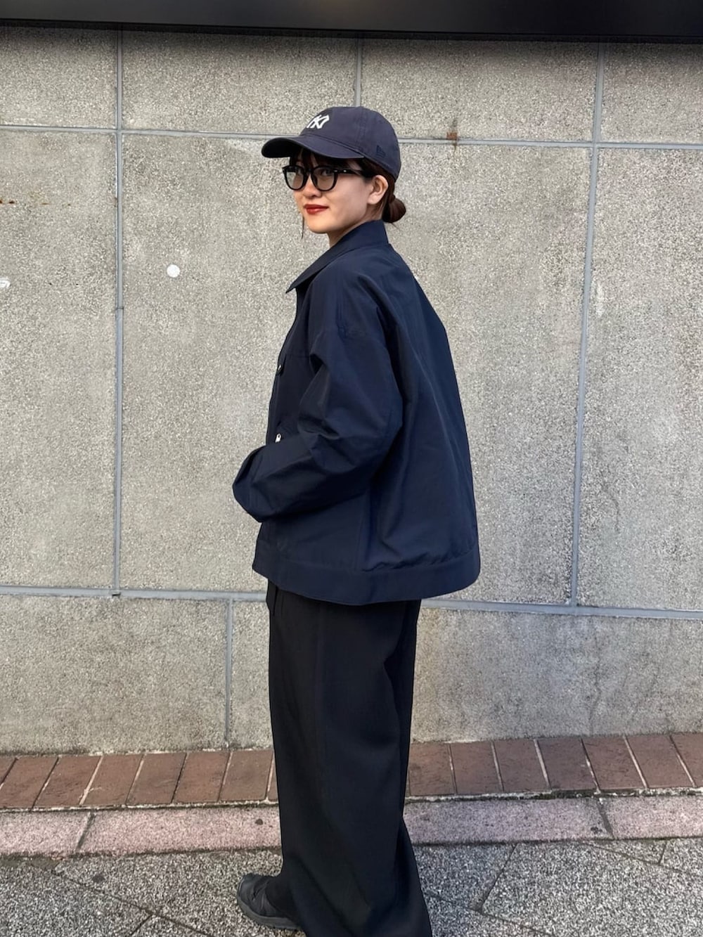 ブラック系のスラックス、ブルー系のブルゾン、ブラック系のサングラスを着用したレディースの冬コーディネートの9枚目の写真