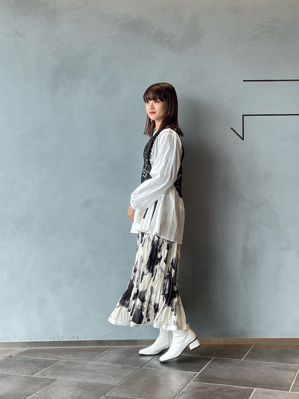 ブラック系のシャツ/ブラウス、ホワイト系のスカート、ホワイト系のブーツを着用したレディースの春コーディネートの4枚目の写真