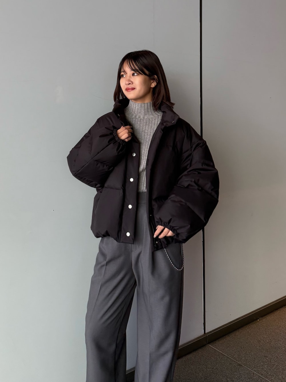 ホワイト系のダウンジャケット/コート、グレー系のスラックス、ブラック系のTシャツ/カットソーを着用したレディースの秋コーディネートの2枚目の写真