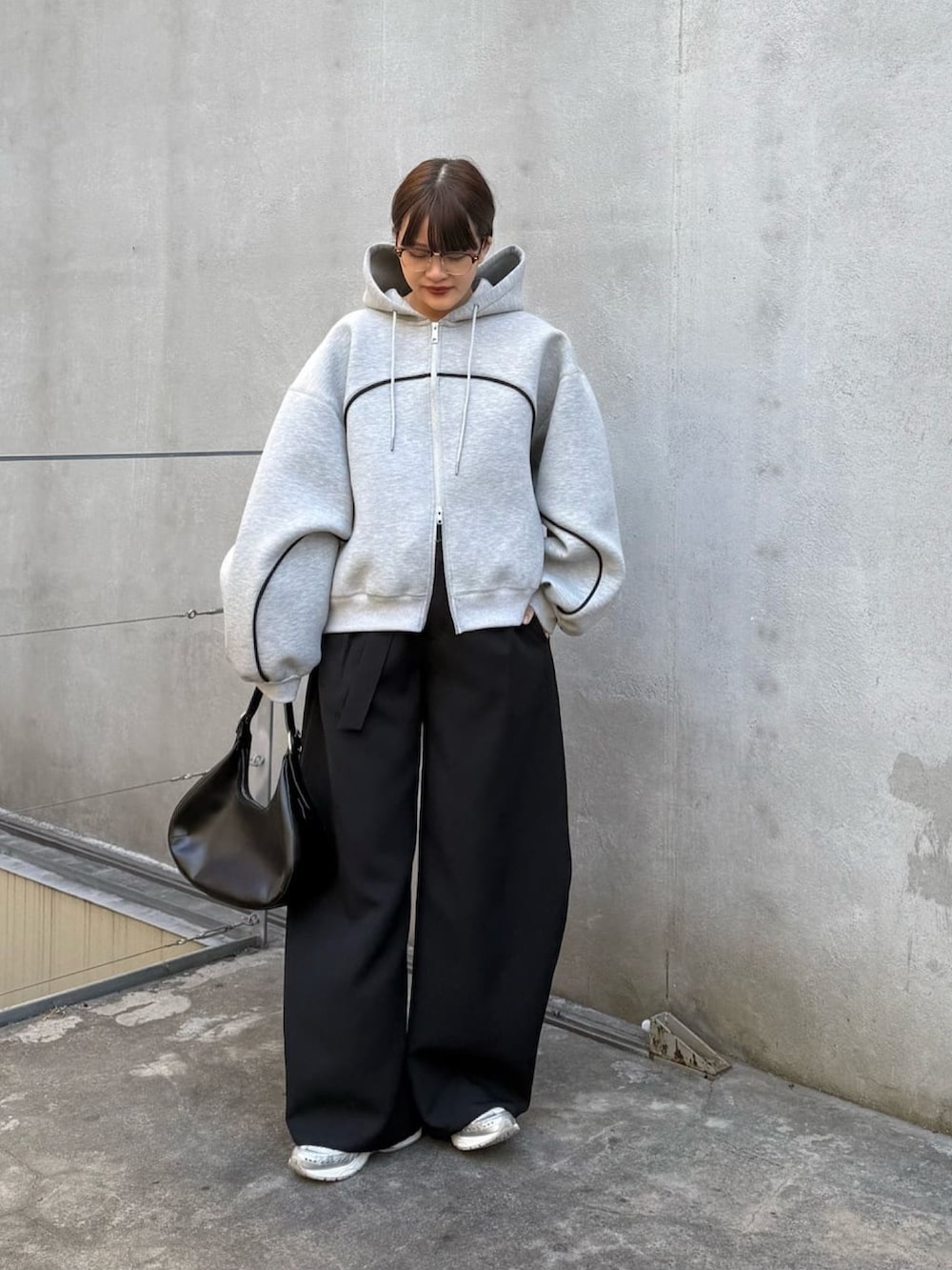 グレー系のパーカー、ブラック系のスラックス、ブラック系のハンドバッグを着用したレディースの冬コーディネートの5枚目の写真