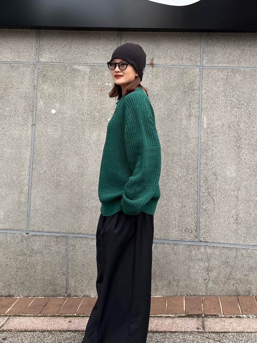 グリーン系のニット/セーター、グレー系のスラックスを着用したレディースの冬コーディネートの4枚目の写真