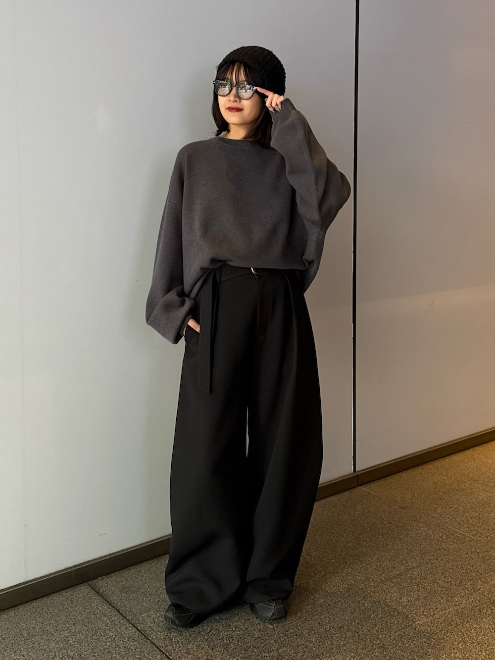 グレー系のニット/セーター、ブラック系のスラックス、ブラック系のサングラスを着用したレディースの秋コーディネートの6枚目の写真