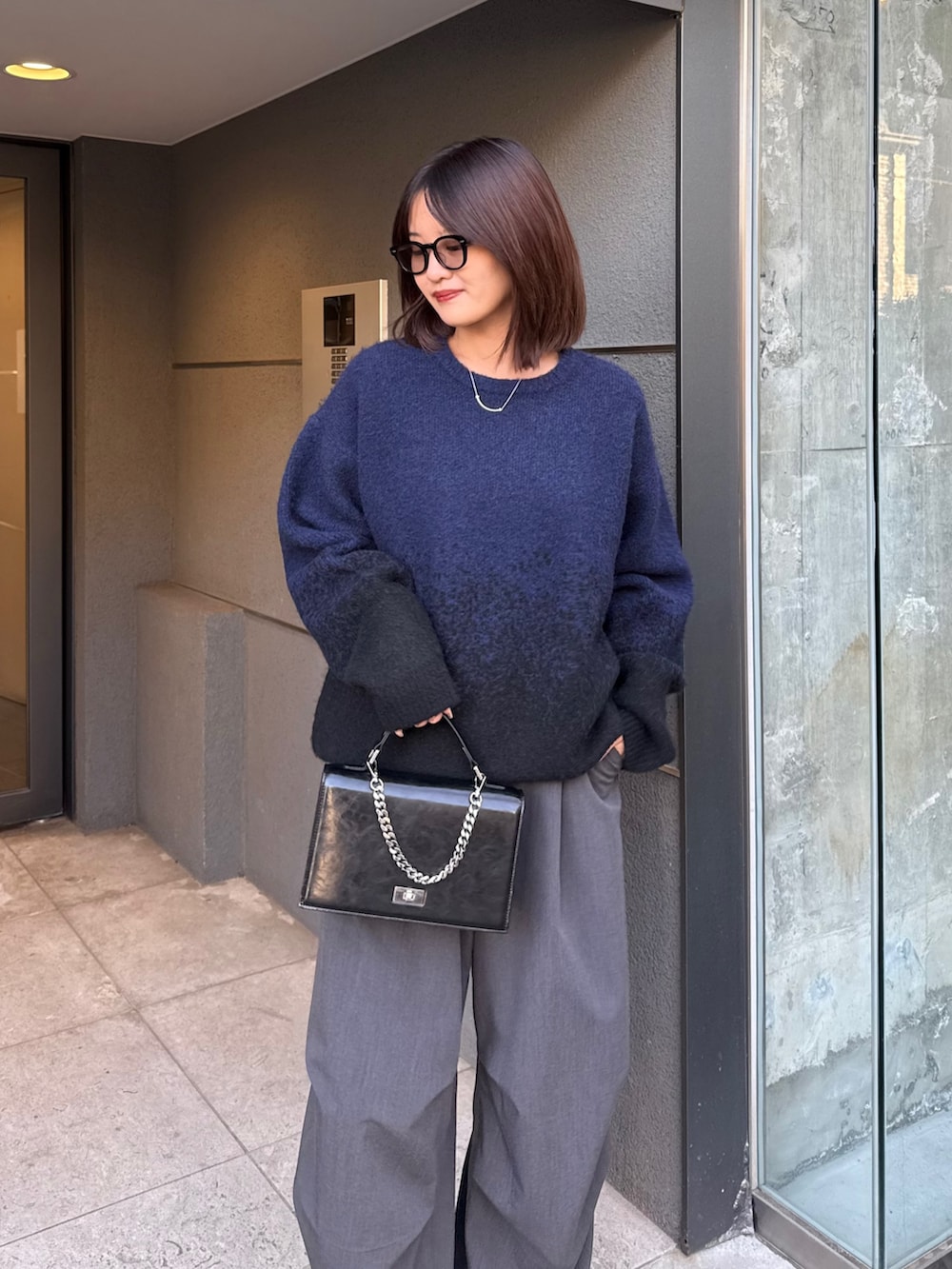 ブラック系のニット/セーター、グレー系のスラックス、ブラック系のショルダーバッグを着用したレディースの冬コーディネートの2枚目の写真