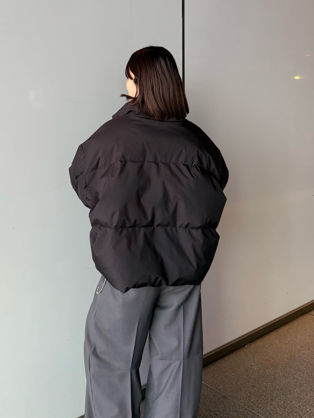 ホワイト系のダウンジャケット/コート、グレー系のスラックス、ブラック系のTシャツ/カットソーを着用したレディースの秋コーディネートの3枚目の写真