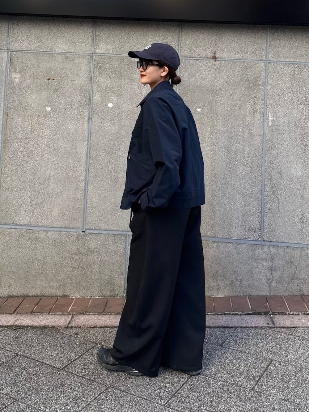 ブラック系のスラックス、ブルー系のブルゾン、ブラック系のサングラスを着用したレディースの冬コーディネートの3枚目の写真