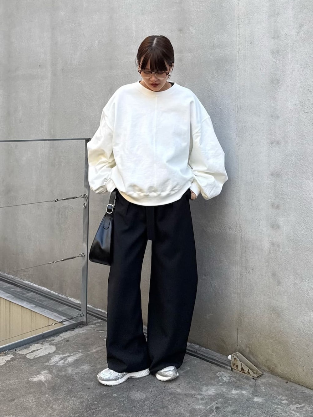 ホワイト系のスウェット、ブラック系のスラックス、ブラック系のハンドバッグを着用したレディースの冬コーディネートの5枚目の写真