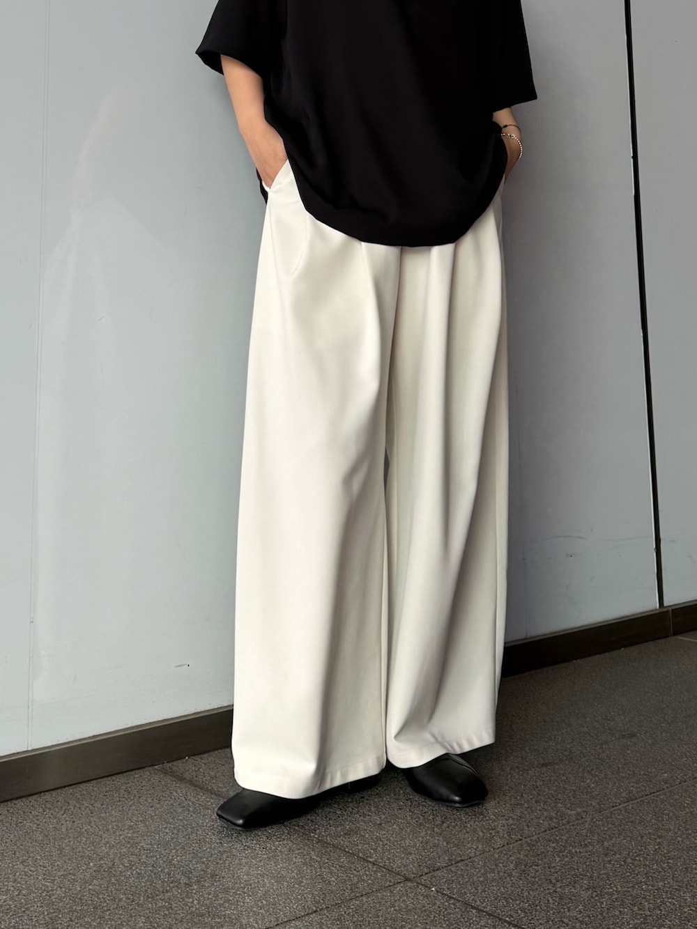 グレー系のスラックス、ブラック系のポロシャツを着用したレディースの春コーディネートの7枚目の写真