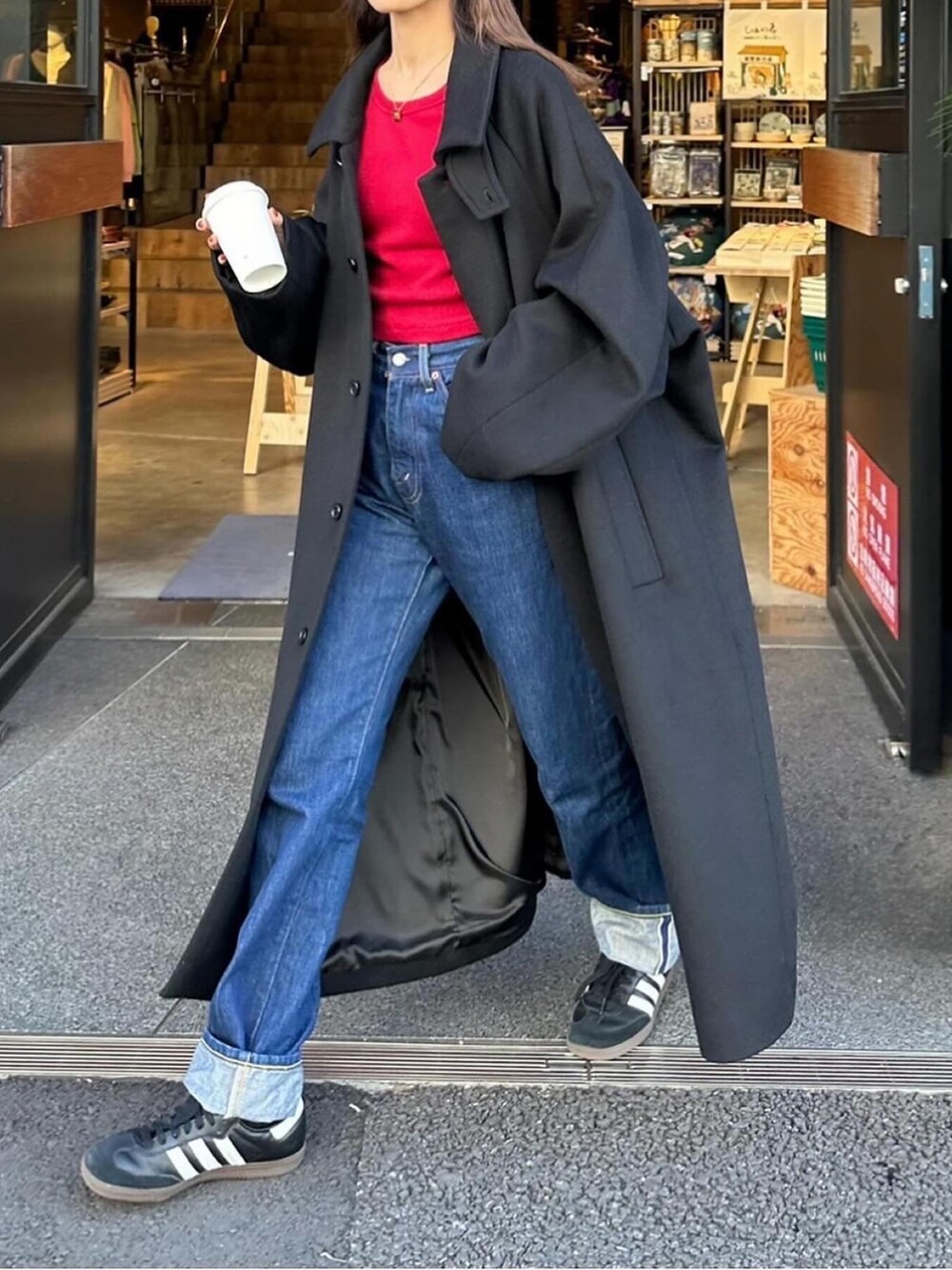 ブラック系のステンカラーコートを着用したレディースの冬コーディネートの3枚目の写真