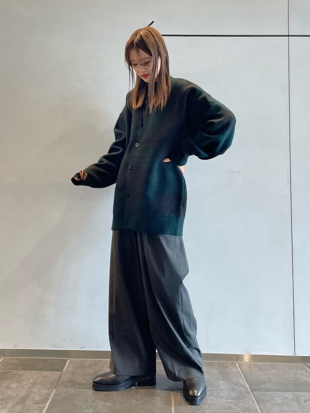 グリーン系のカーディガン/ボレロ、グレー系のスラックス、ブラック系のブーツを着用したレディースの秋コーディネートの2枚目の写真