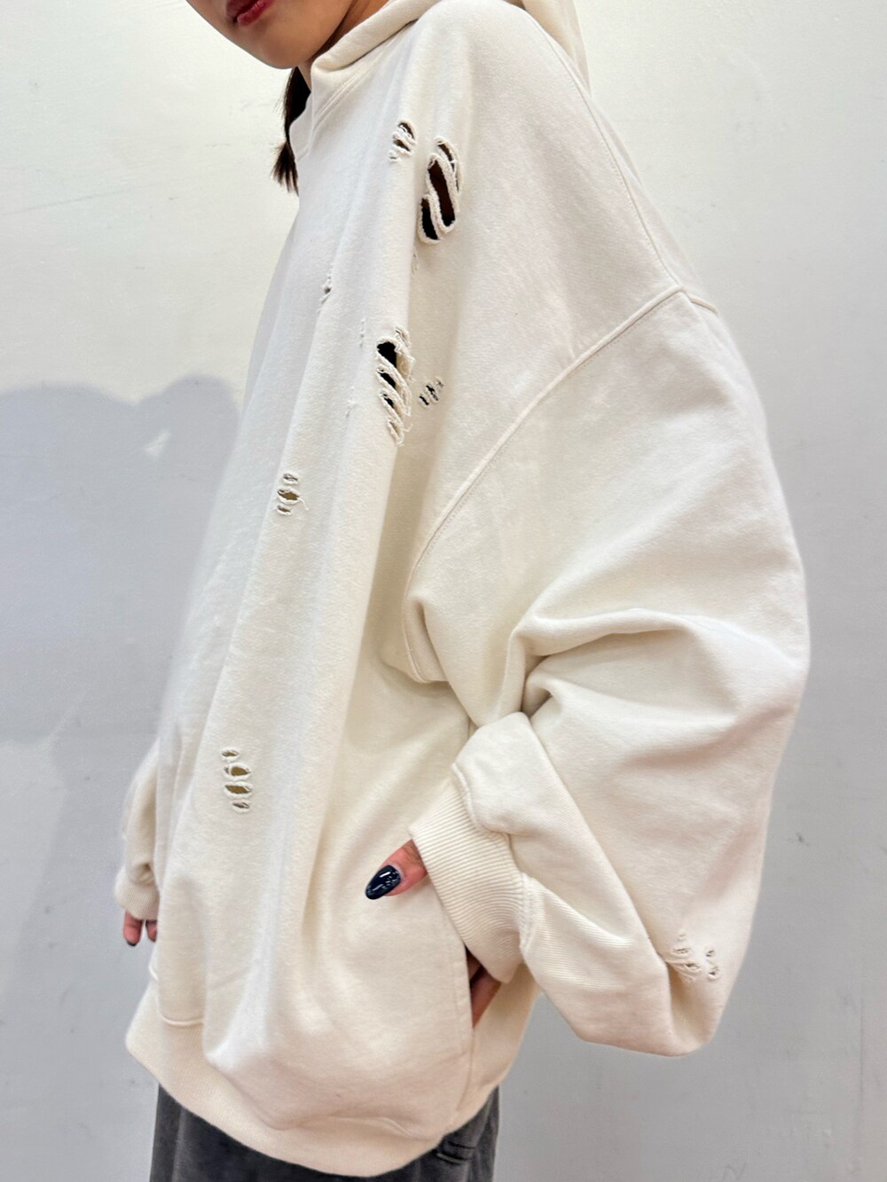 ホワイト系のパーカー、ブラック系のデニムパンツを着用したレディースの秋コーディネートの2枚目の写真