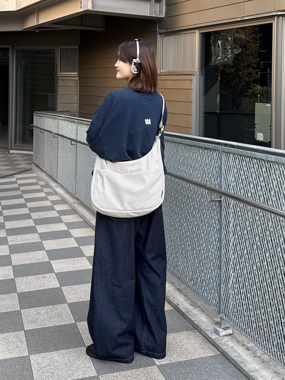 ブルー系のスウェット、グレー系のショルダーバッグ、ブルー系のデニムパンツを着用したレディースの冬コーディネートの2枚目の写真