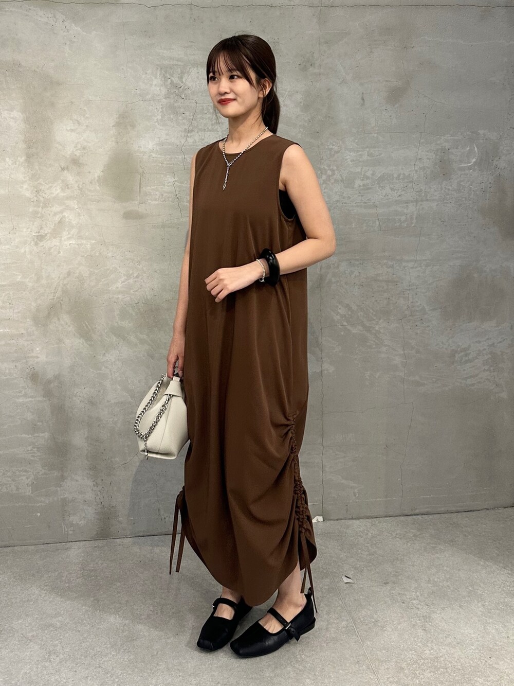 ブラウン系のワンピース、ブラック系のショルダーバッグ、ブラック系のブレスレットを着用したレディースの春コーディネートの2枚目の写真