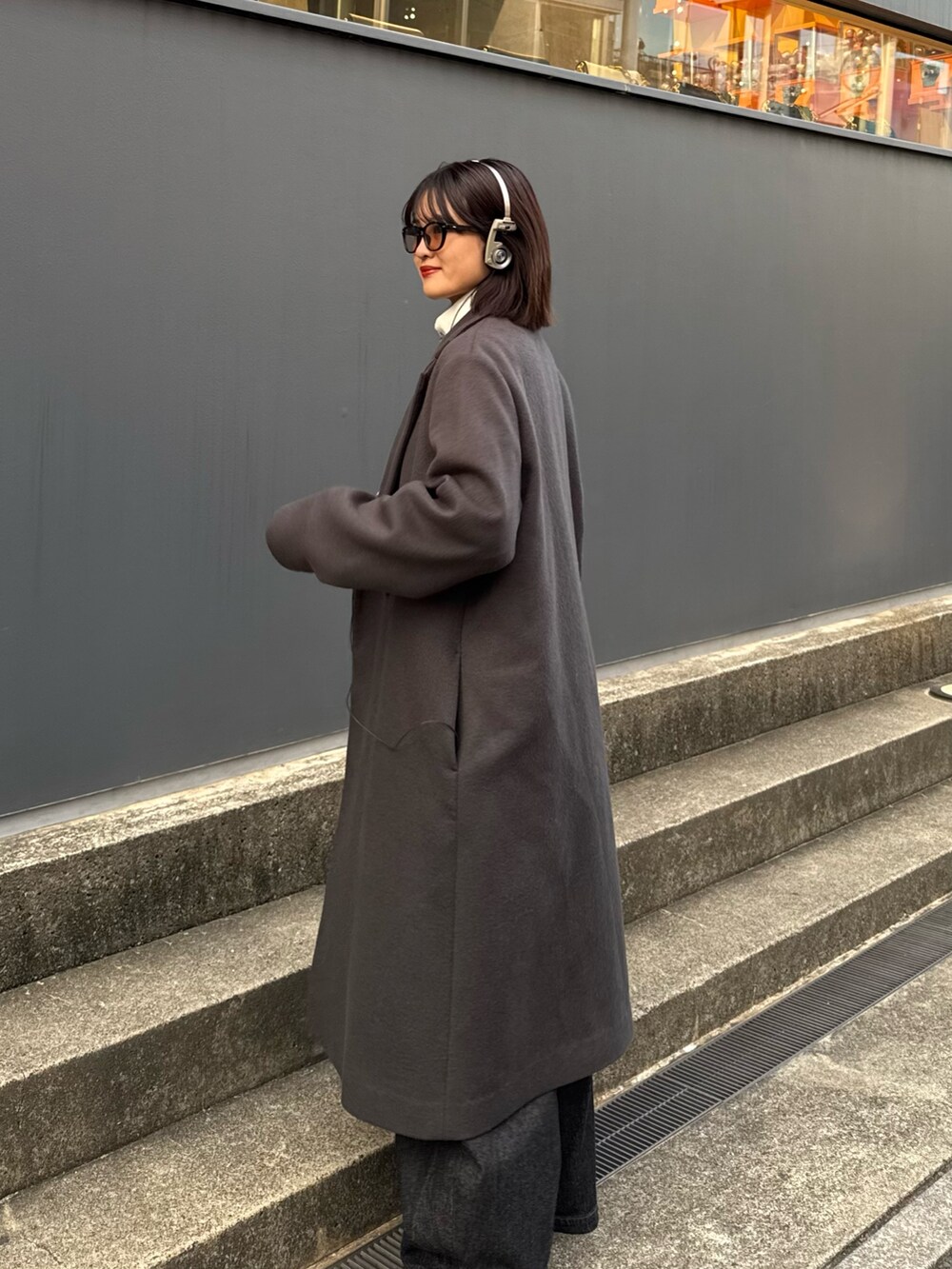 グレー系のチェスターコート、ホワイト系のニット/セーター、ブラック系のデニムパンツを着用したレディースの秋コーディネートの6枚目の写真