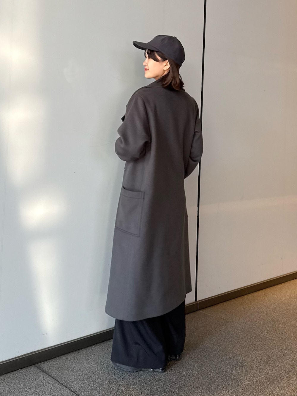 グレー系のニット/セーター、ブラック系のチェスターコート、ブラック系のスラックスを着用したレディースの冬コーディネートの2枚目の写真
