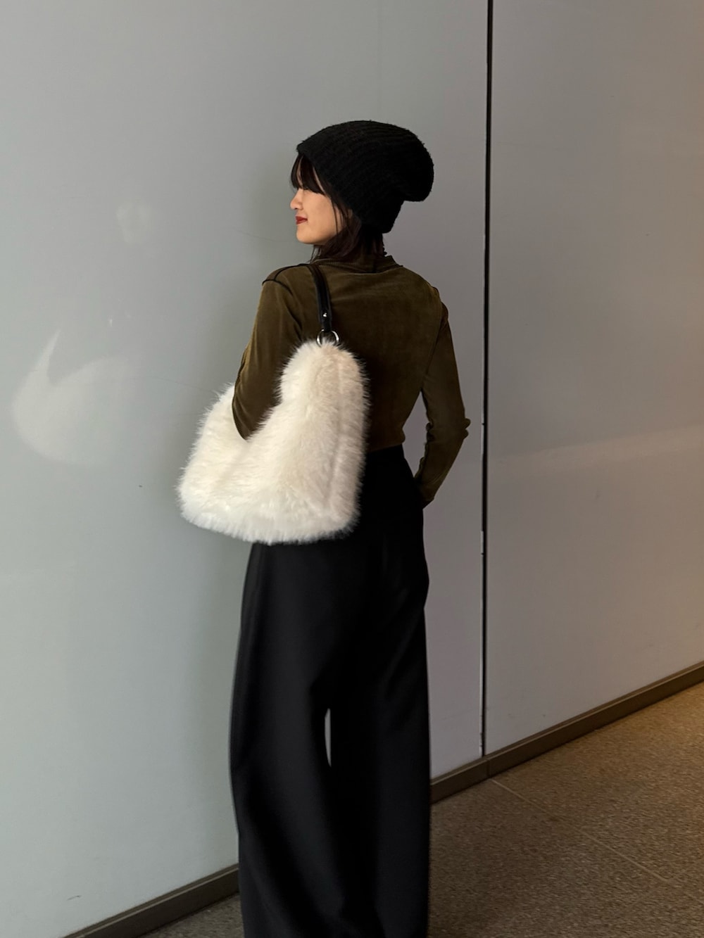 ブラック系のスラックス、ブラウン系のトートバッグ、グリーン系のTシャツ/カットソーを着用したレディースの秋コーディネートの5枚目の写真