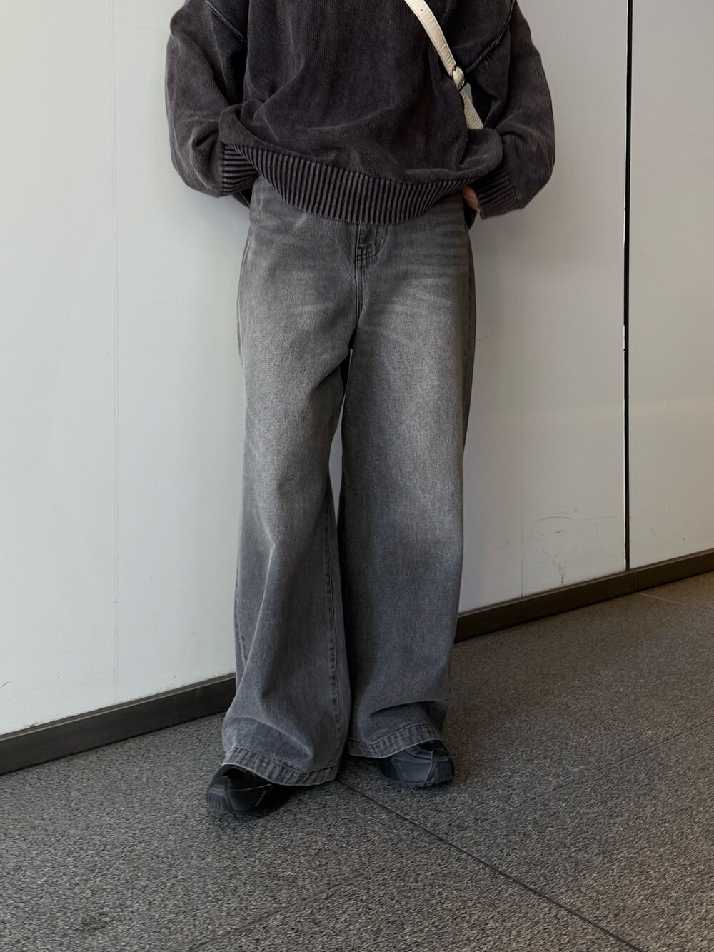 ブラック系のデニムパンツ、ブラック系のニット/セーター、ホワイト系のショルダーバッグを着用したレディースの秋コーディネートの5枚目の写真