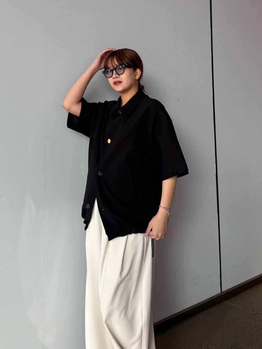 ブラック系のシャツ/ブラウス、グレー系のスラックスを着用したレディースの春コーディネートの3枚目の写真