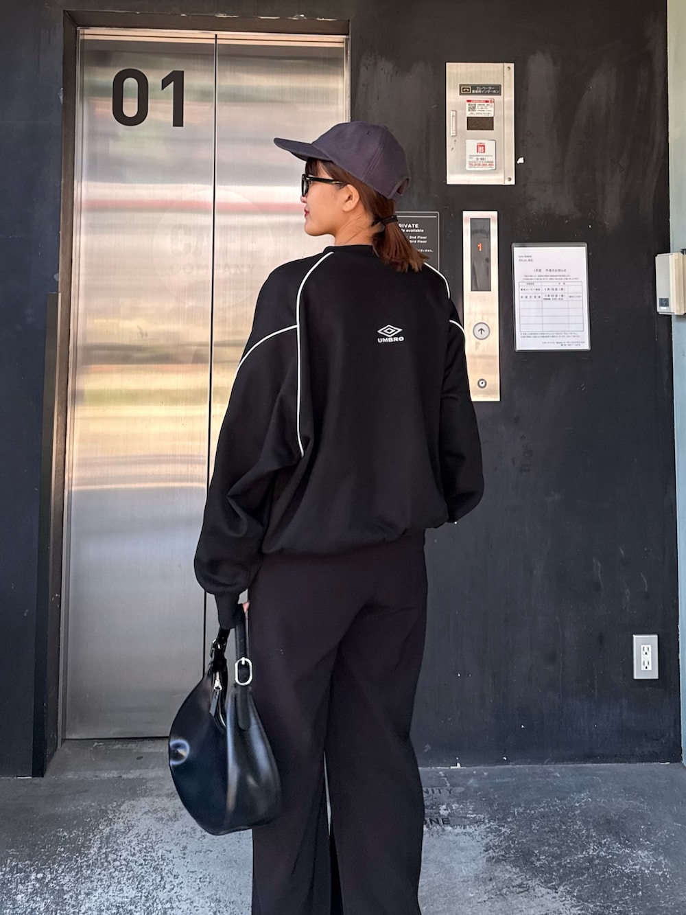 ブルー系のスウェット、ブラック系のハンドバッグ、ブラック系のサングラスを着用したレディースの冬コーディネートの4枚目の写真