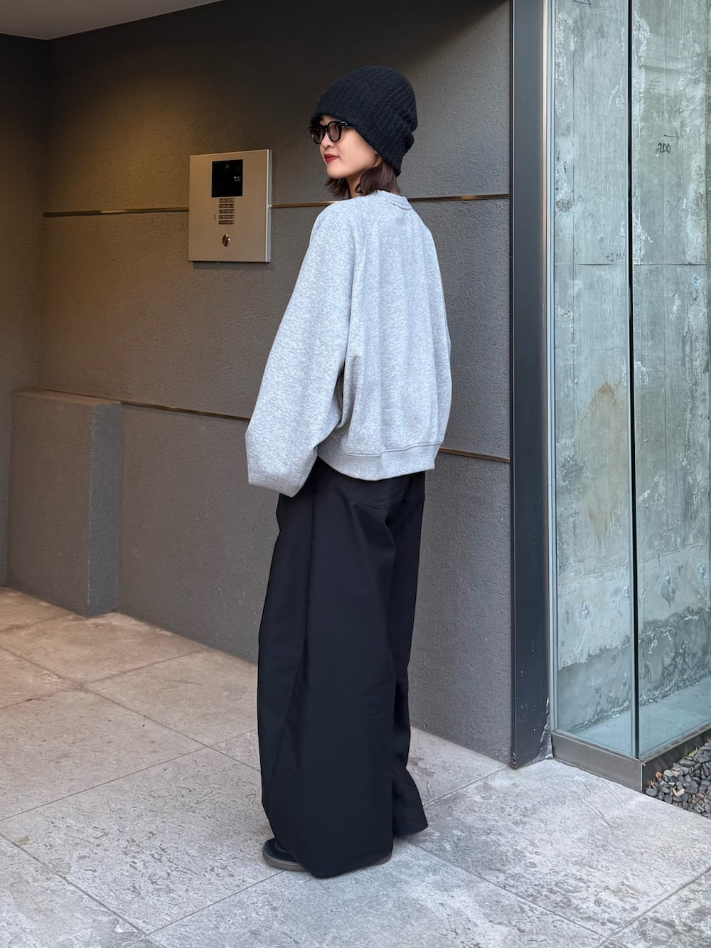 グレー系のスウェット、ブラック系のスラックス、ブラック系のサングラスを着用したレディースの冬コーディネートの6枚目の写真