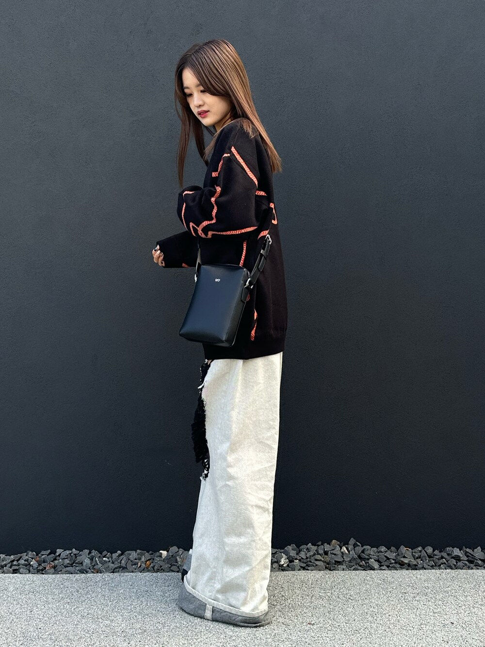 ブラック系のニット/セーター、ブラック系のショルダーバッグ、ブルー系のデニムパンツを着用したレディースの冬コーディネートの3枚目の写真