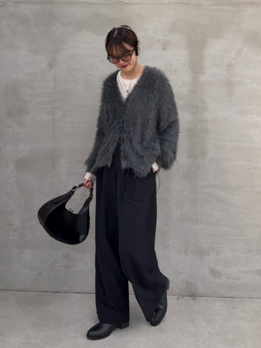 グレー系のカーディガン/ボレロ、ホワイト系のニット/セーター、ブラック系のスラックスを着用したレディースの秋コーディネートの2枚目の写真