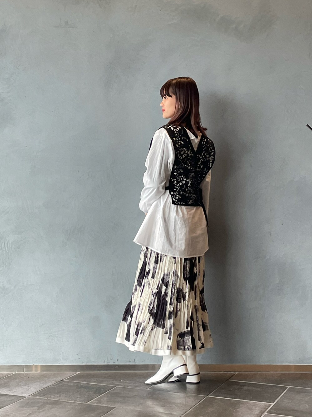 ブラック系のシャツ/ブラウス、ホワイト系のスカート、ホワイト系のブーツを着用したレディースの春コーディネートの2枚目の写真